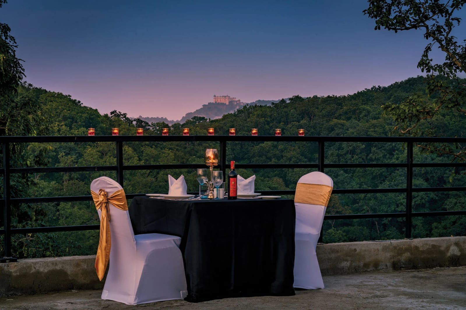 Candlelit private dinner setup with Kumbhalgarh Fort silhouette on the horizon