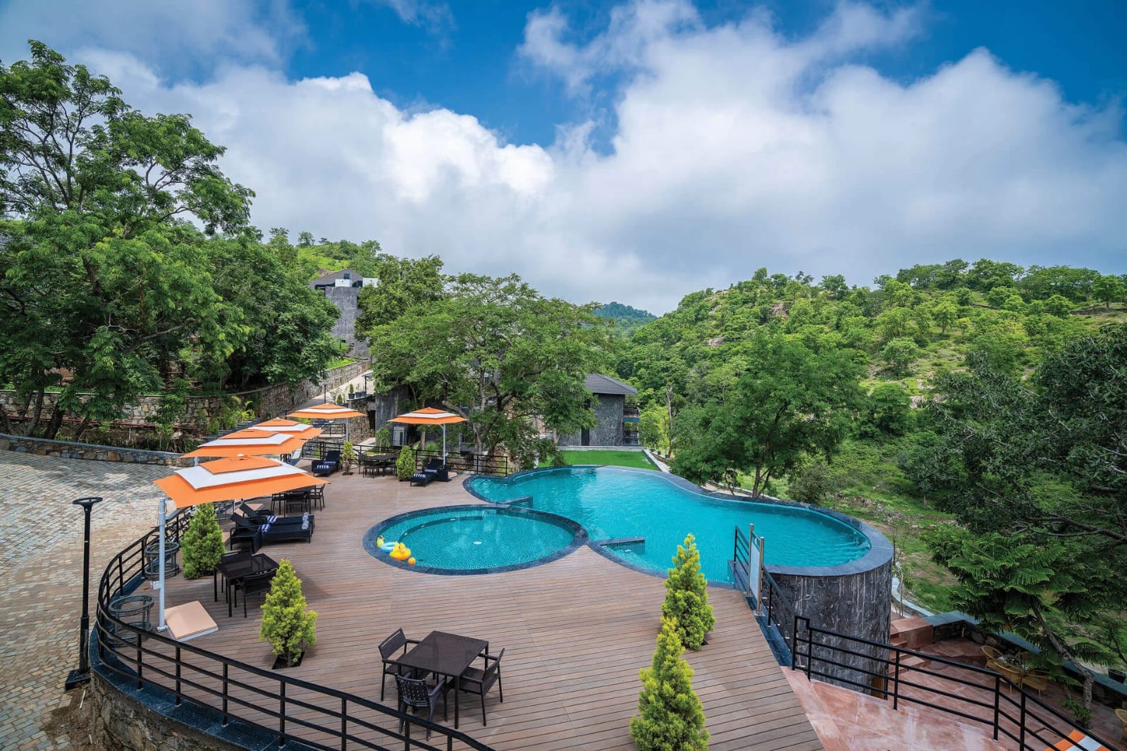 Infinity pool with orange cabanas overlooking the Kumbhalgarh forest
